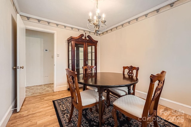 dining space featuring baseboards, ornamental molding, light wood-type flooring, and an inviting chandelier