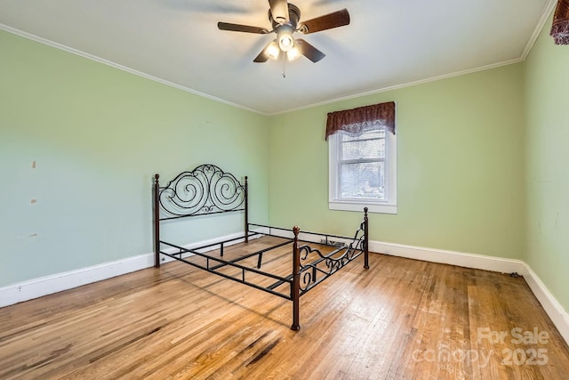 unfurnished bedroom with baseboards, hardwood / wood-style flooring, ceiling fan, crown molding, and a baseboard heating unit