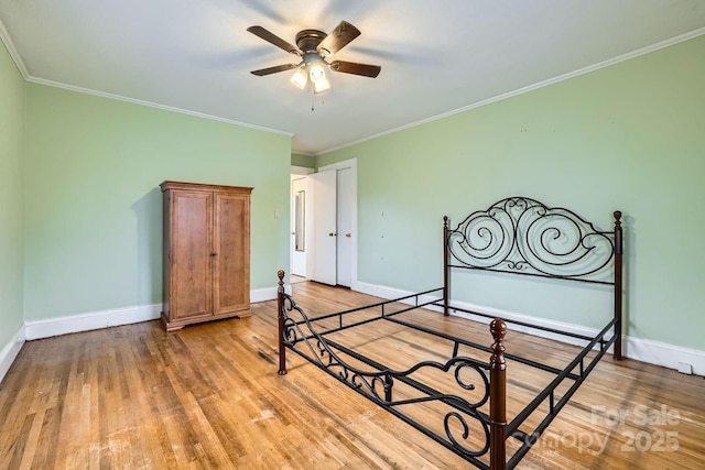 bedroom featuring crown molding, light wood-style flooring, and baseboards