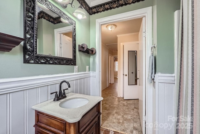 bathroom with a wainscoted wall, ornamental molding, and vanity