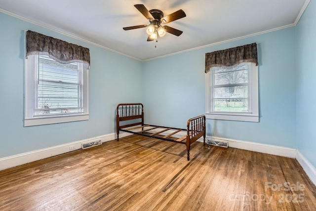 unfurnished bedroom featuring multiple windows, crown molding, and wood finished floors