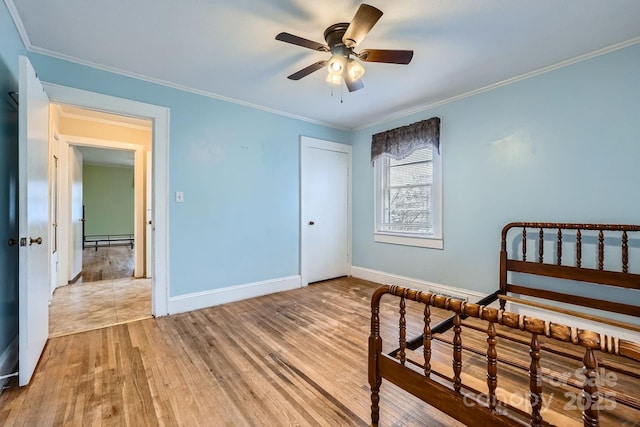 bedroom with a baseboard radiator, crown molding, baseboards, and wood finished floors