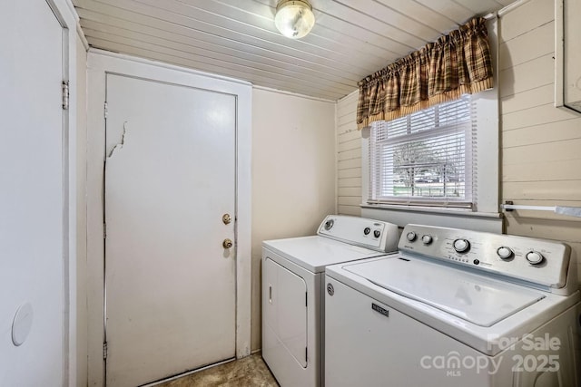 clothes washing area featuring laundry area, wood walls, wooden ceiling, and washing machine and dryer