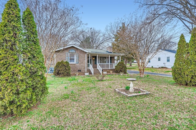 view of front of house with covered porch, brick siding, crawl space, a chimney, and a front yard