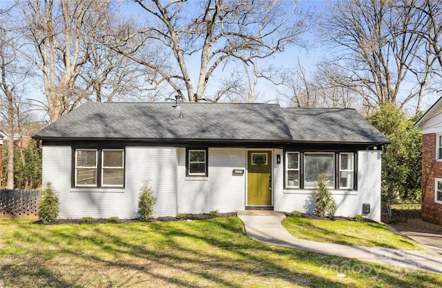 single story home with brick siding, a front lawn, and roof with shingles