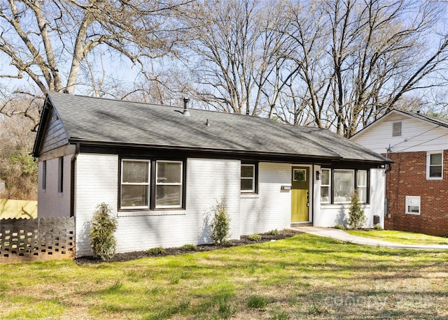 ranch-style home with a front yard, brick siding, and roof with shingles