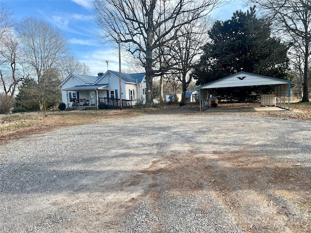 exterior space with a porch, gravel driveway, and a detached carport