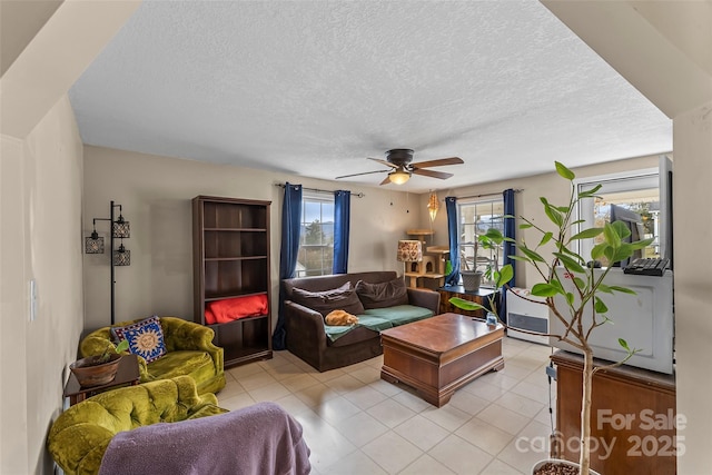 living room with light tile patterned flooring, a textured ceiling, and a ceiling fan