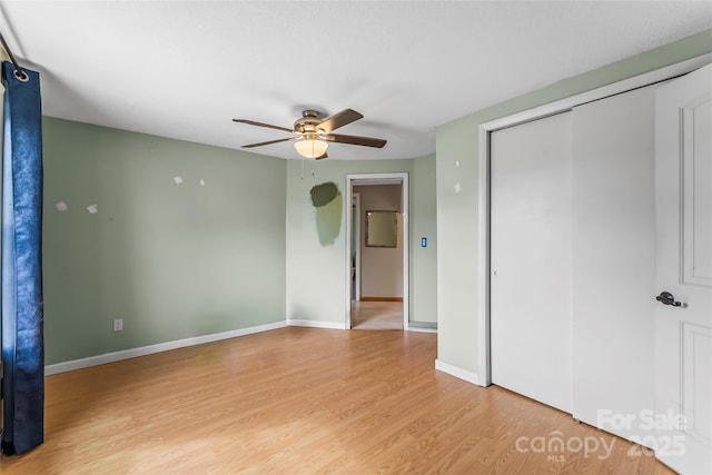 unfurnished bedroom with baseboards, light wood-type flooring, a closet, and ceiling fan