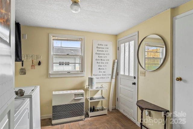 interior space with baseboards, heating unit, a textured ceiling, and independent washer and dryer