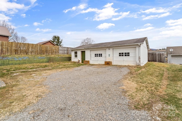 view of front facade featuring a detached garage, an outbuilding, and fence