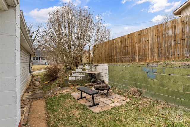 view of yard featuring a patio, a fire pit, and fence