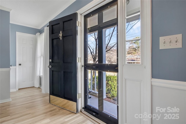 foyer entrance with ornamental molding, light wood-type flooring, and baseboards