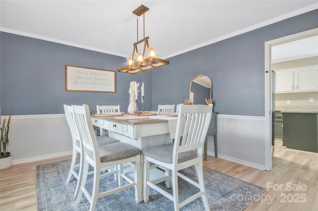 dining room featuring baseboards, a notable chandelier, crown molding, and light wood finished floors