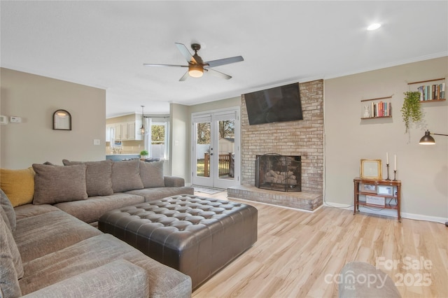 living area featuring a fireplace, baseboards, french doors, light wood-type flooring, and crown molding