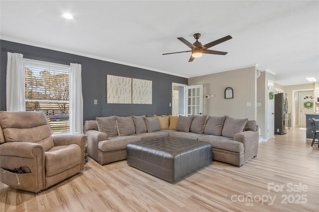 living room featuring light wood finished floors, ceiling fan, baseboards, and crown molding