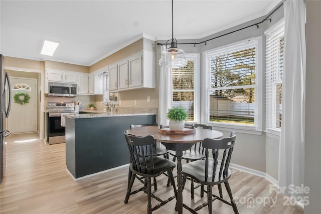 kitchen with a peninsula, light wood-type flooring, appliances with stainless steel finishes, and hanging light fixtures