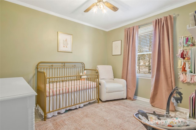 bedroom with baseboards, a crib, a ceiling fan, and crown molding