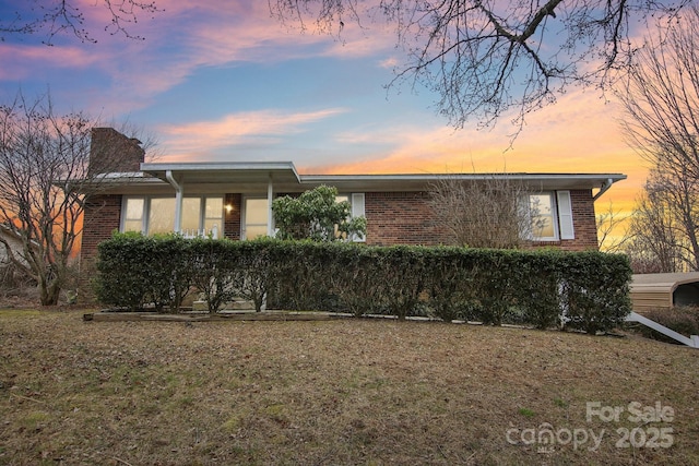 view of front of property featuring brick siding and a chimney