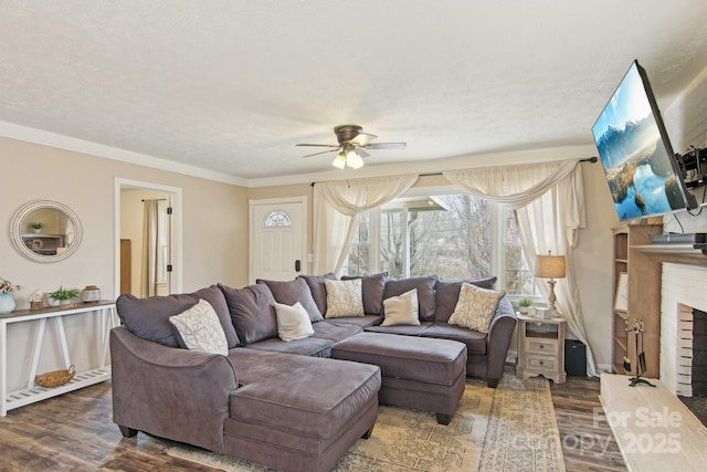 living room with ceiling fan, ornamental molding, wood finished floors, a textured ceiling, and a fireplace