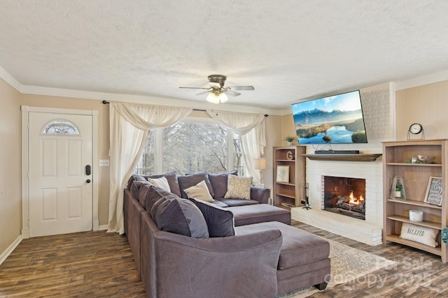 living area with a brick fireplace, ceiling fan, a textured ceiling, and dark wood-style flooring