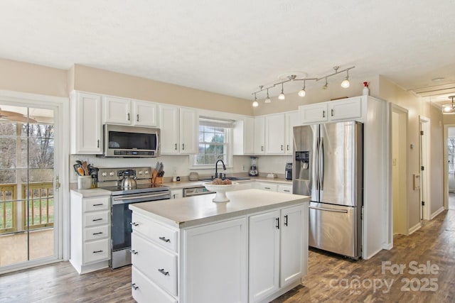 kitchen featuring appliances with stainless steel finishes, dark wood-style flooring, light countertops, white cabinetry, and a sink