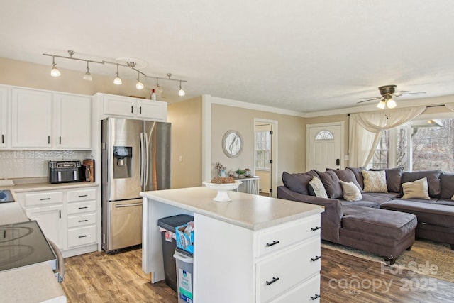 kitchen featuring range with electric cooktop, light wood-style floors, light countertops, stainless steel refrigerator with ice dispenser, and a center island