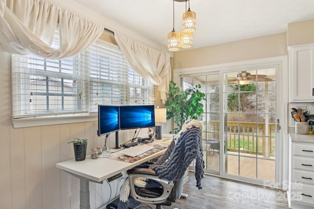 office featuring a healthy amount of sunlight, wood finished floors, and ceiling fan with notable chandelier