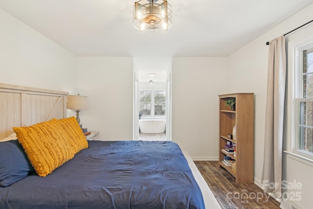 bedroom with baseboards, ensuite bath, and wood finished floors