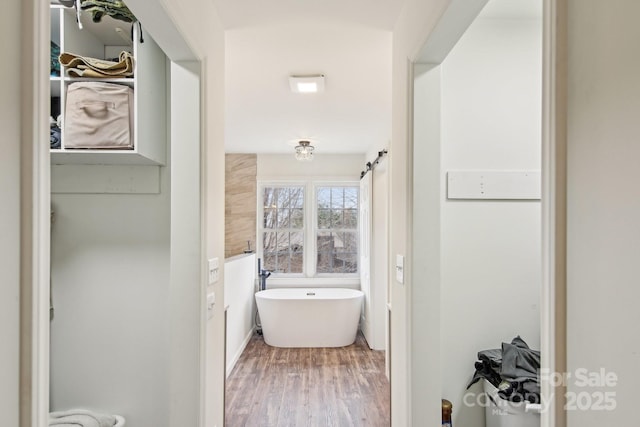 bathroom with a freestanding bath and wood finished floors