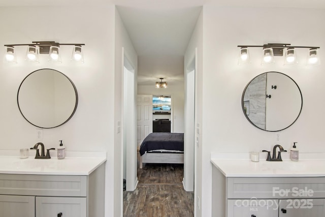 bathroom with wood finished floors, ensuite bath, two vanities, and a sink