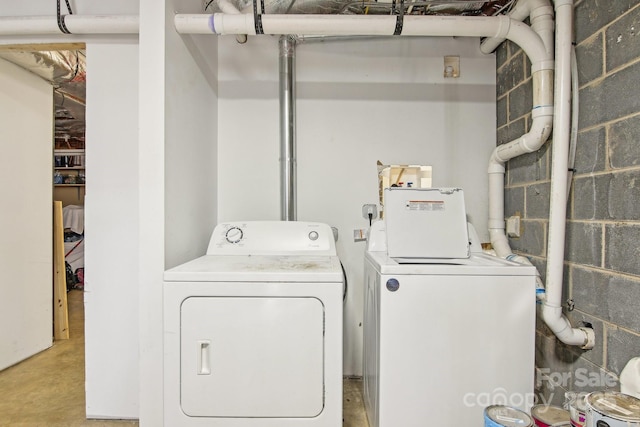 washroom featuring concrete block wall, laundry area, and washing machine and clothes dryer