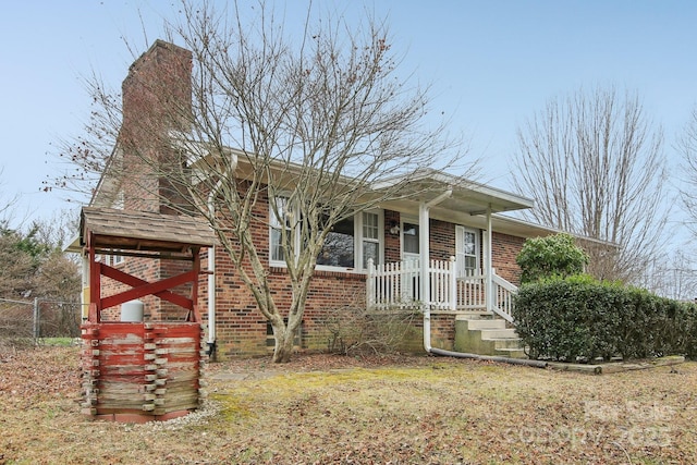 view of front of home with a chimney, fence, and brick siding