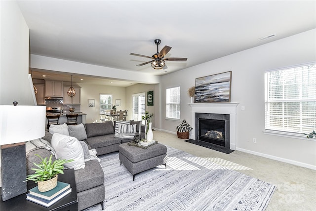 living area with visible vents, baseboards, a healthy amount of sunlight, and a fireplace with flush hearth