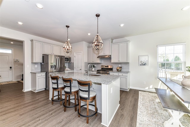 kitchen featuring a sink, backsplash, a breakfast bar, appliances with stainless steel finishes, and dark wood-style flooring