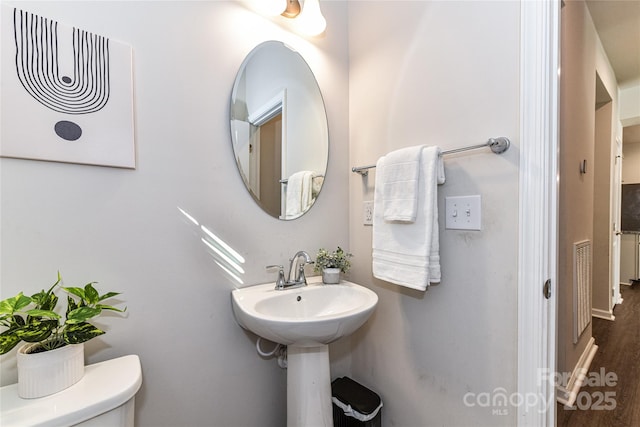 half bath with visible vents, toilet, and wood finished floors