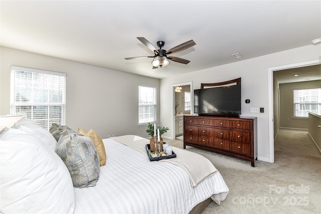 bedroom with ensuite bath, a ceiling fan, baseboards, and light carpet