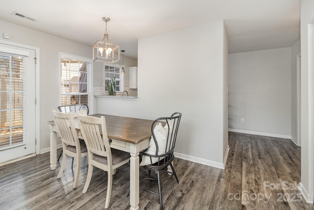 dining area featuring a chandelier, dark wood finished floors, and baseboards