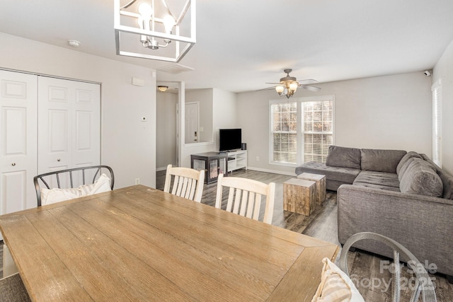 dining area featuring ceiling fan with notable chandelier, wood finished floors, and baseboards