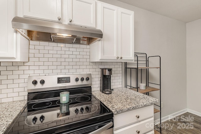 kitchen with stainless steel electric range oven, baseboards, white cabinets, and exhaust hood