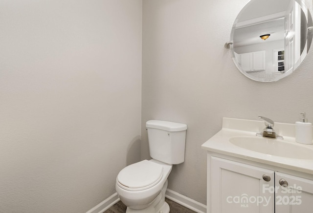 half bathroom featuring vanity, toilet, and baseboards