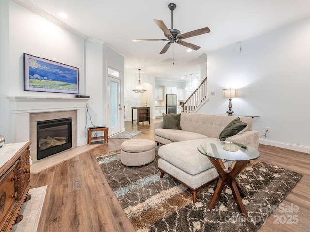 living room featuring a fireplace, stairway, wood finished floors, and baseboards