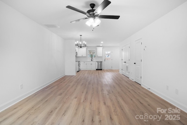 unfurnished living room featuring visible vents, light wood-style flooring, ceiling fan with notable chandelier, and baseboards