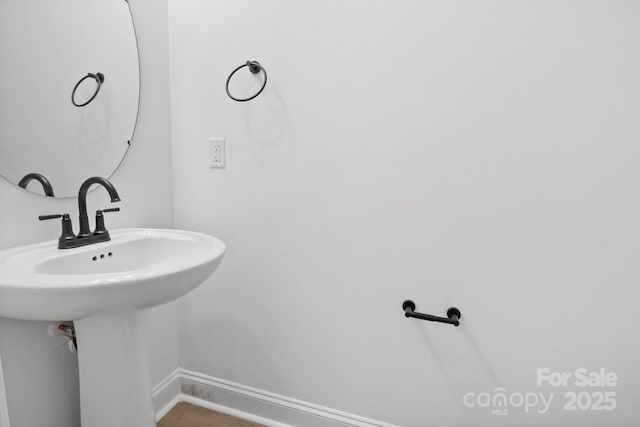 bathroom with a sink, baseboards, and wood finished floors