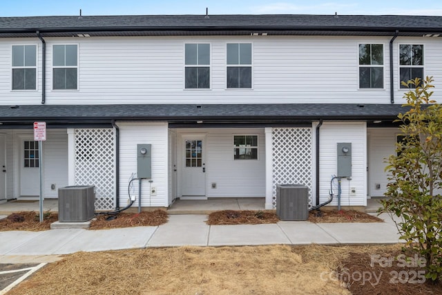 townhome / multi-family property featuring roof with shingles and central AC unit