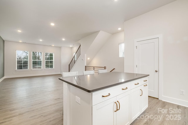 kitchen with white cabinets, dark countertops, a kitchen island, light wood-style floors, and recessed lighting