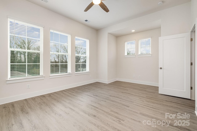 unfurnished room with visible vents, a ceiling fan, light wood-style flooring, and baseboards