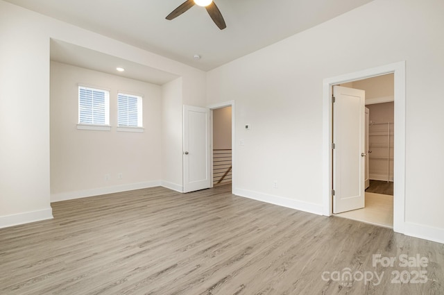 empty room with light wood-style floors, baseboards, and a ceiling fan