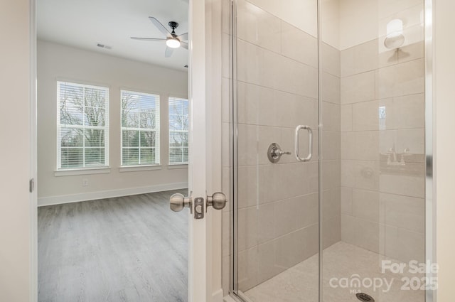 bathroom with visible vents, ceiling fan, a shower stall, wood finished floors, and baseboards