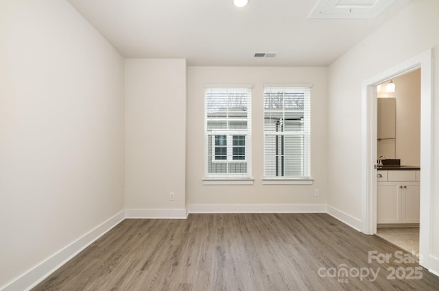 empty room featuring wood finished floors, visible vents, and baseboards